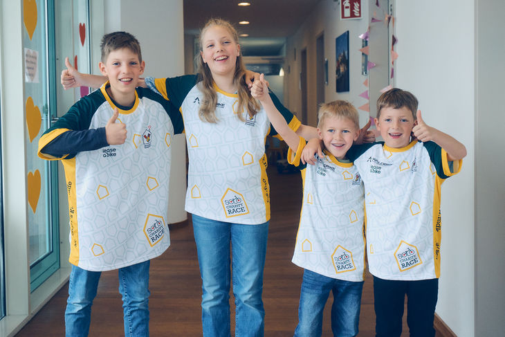 Teilnehmer mit SOLO Charity Race Shirts Vier Personen in SOLO Charity Race T-Shirts geben in einem Gang Thumbs-up.